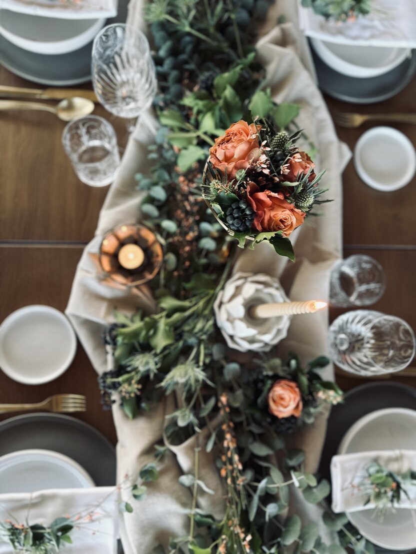hochzeitlich gedeckter Tisch mit Grünzweig und Blumenstrauß