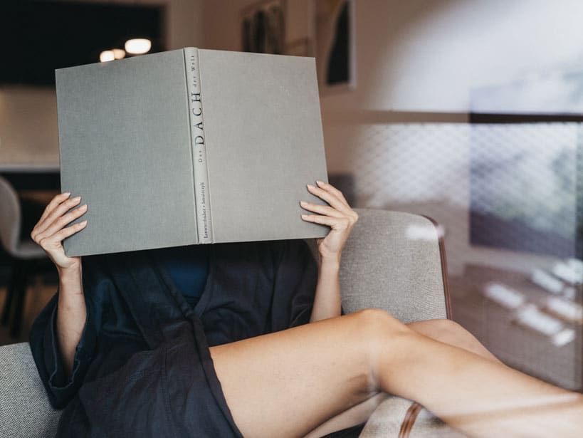 Frau entspannt im Appartement und liest ein großes Buch