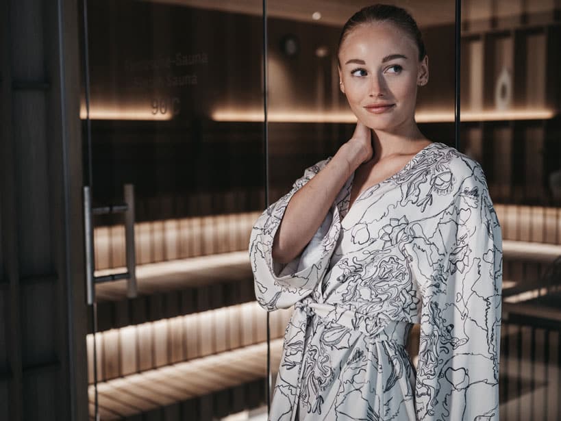 Frau mit Hand im Nacken vor der Sauna